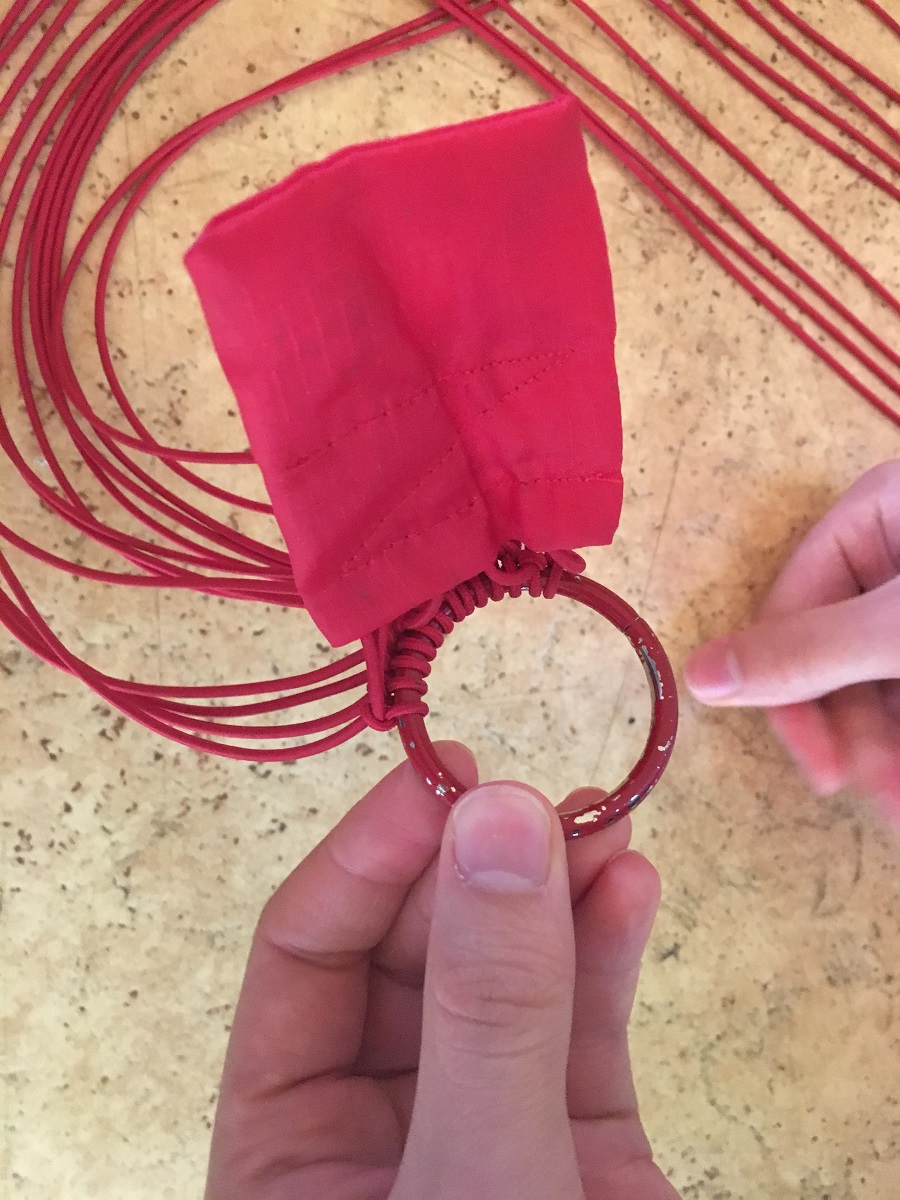 Close-up photo showing the threads knotted to a red ring.