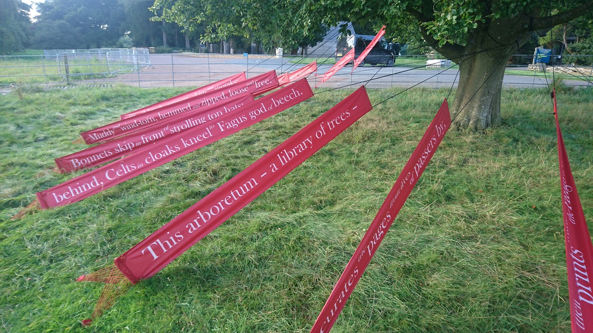 Photo showing a close-up view of banners from the poem 'Beech Book'. The banners have been placed in a semi-circle around the tree like a maypole.
